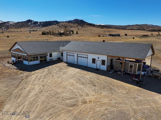 view of front facade featuring a garage, a mountain view, and a sunroom