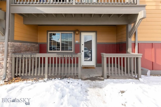 snow covered property entrance featuring a balcony