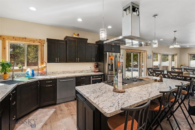 kitchen featuring decorative light fixtures, a center island, a breakfast bar area, island range hood, and appliances with stainless steel finishes