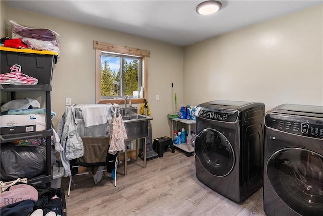 laundry area with separate washer and dryer and light hardwood / wood-style floors