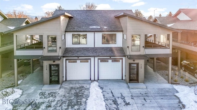 snow covered property with a balcony and a garage