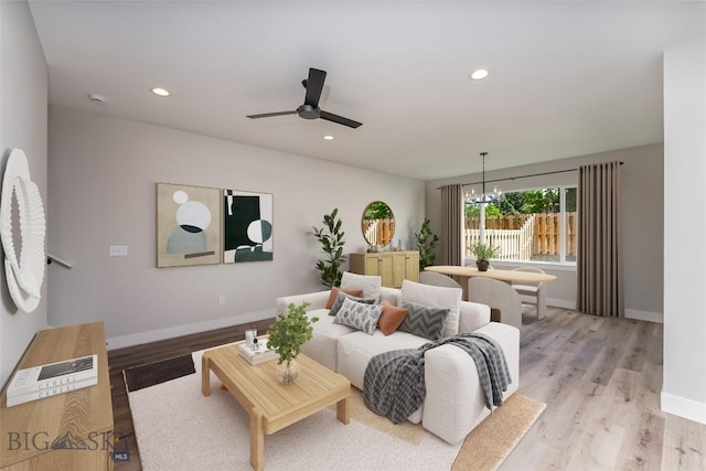 living room featuring light hardwood / wood-style flooring and ceiling fan with notable chandelier