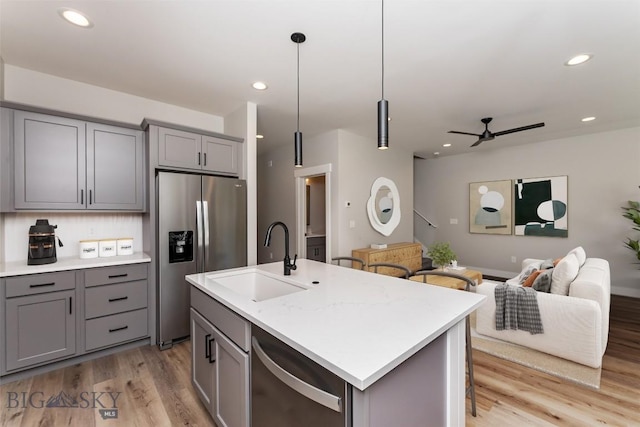 kitchen with sink, stainless steel appliances, an island with sink, and decorative light fixtures