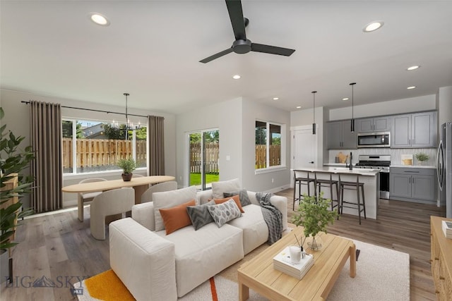 living room with ceiling fan with notable chandelier and hardwood / wood-style flooring