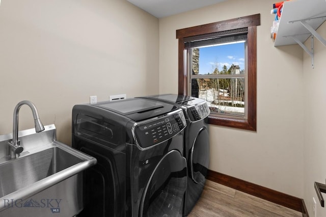 laundry area with washer and dryer, light hardwood / wood-style flooring, and sink