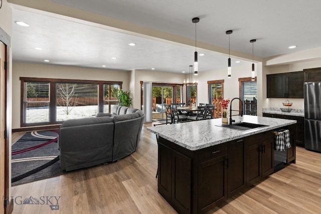 kitchen with an island with sink, fridge, light hardwood / wood-style flooring, and sink