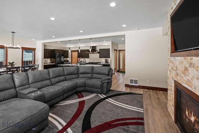 living room with a stone fireplace and hardwood / wood-style floors