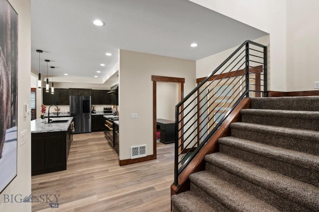 stairs with hardwood / wood-style flooring and sink