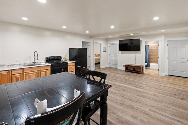 kitchen with light wood-type flooring, tile countertops, black appliances, and sink