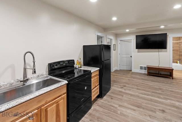 kitchen featuring black appliances, light hardwood / wood-style floors, and sink