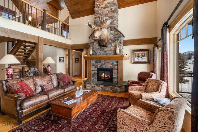 living room featuring a stone fireplace, stairway, a towering ceiling, and wood finished floors