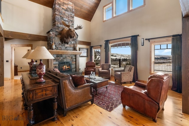 interior space with a wealth of natural light, a stone fireplace, wood finished floors, and wood ceiling