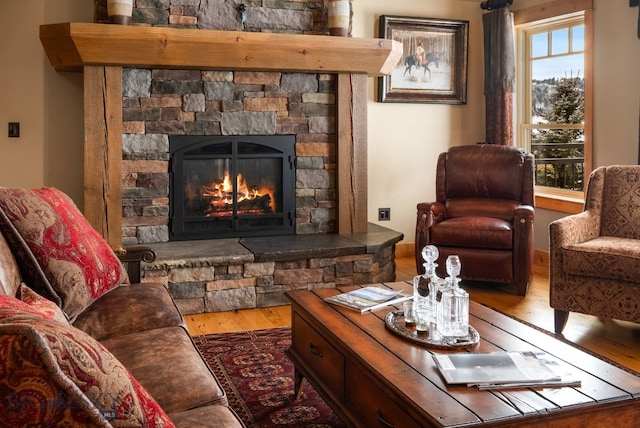 living area with a stone fireplace and wood finished floors