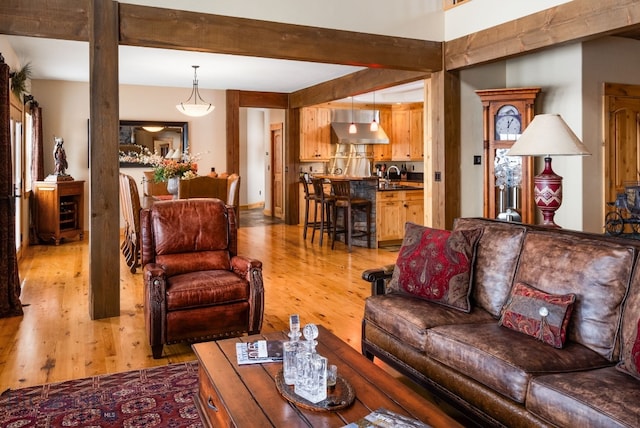 living room with beamed ceiling and light wood-style flooring