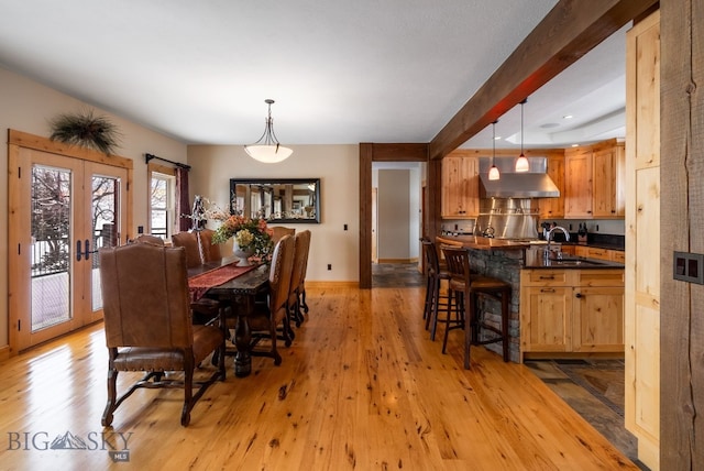 dining room featuring light wood-type flooring, french doors, baseboards, and beamed ceiling