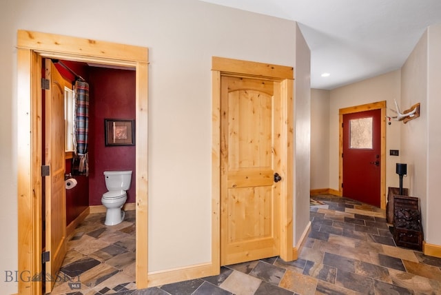 foyer entrance with baseboards and stone tile flooring