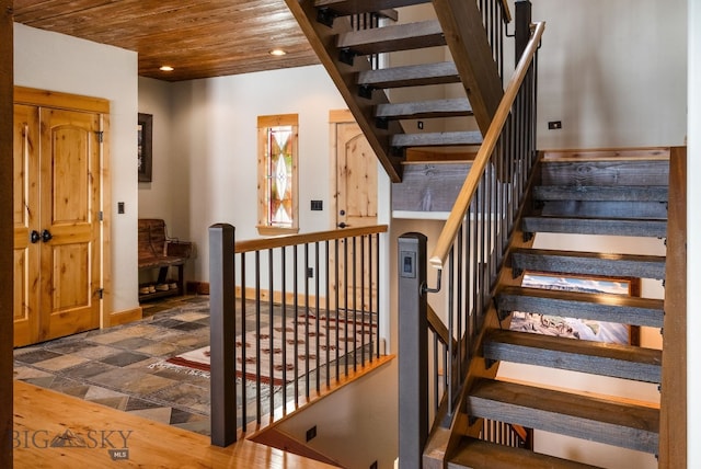 stairway with stone tile floors, recessed lighting, wood ceiling, and baseboards