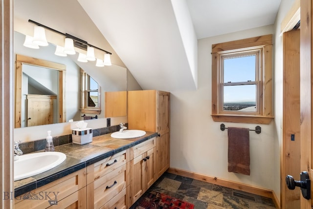 bathroom featuring a sink, visible vents, baseboards, and stone tile floors