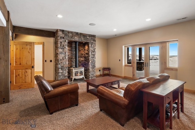 living area with visible vents, french doors, baseboards, light colored carpet, and a wood stove