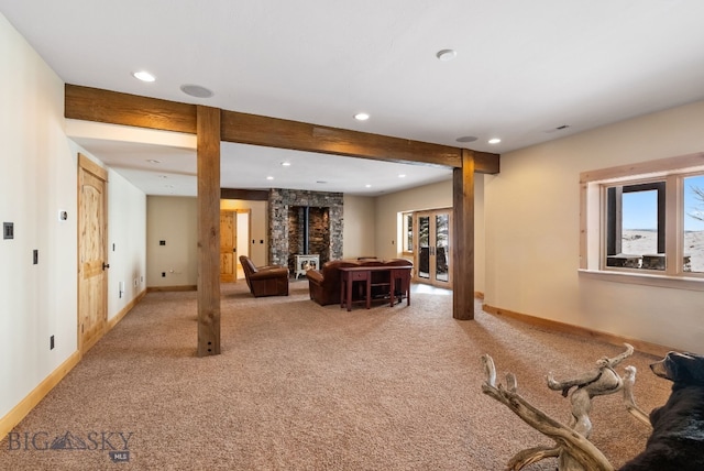 living area with beam ceiling, light carpet, a wood stove, and baseboards