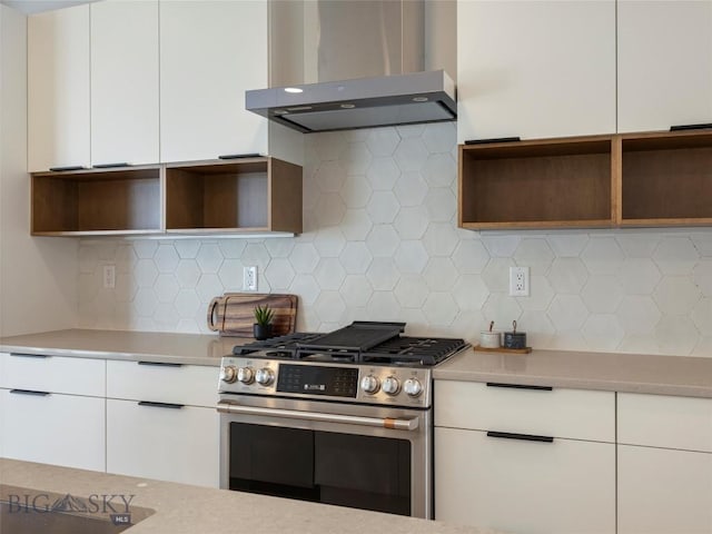 kitchen featuring white cabinets, ventilation hood, stainless steel gas stove, and tasteful backsplash