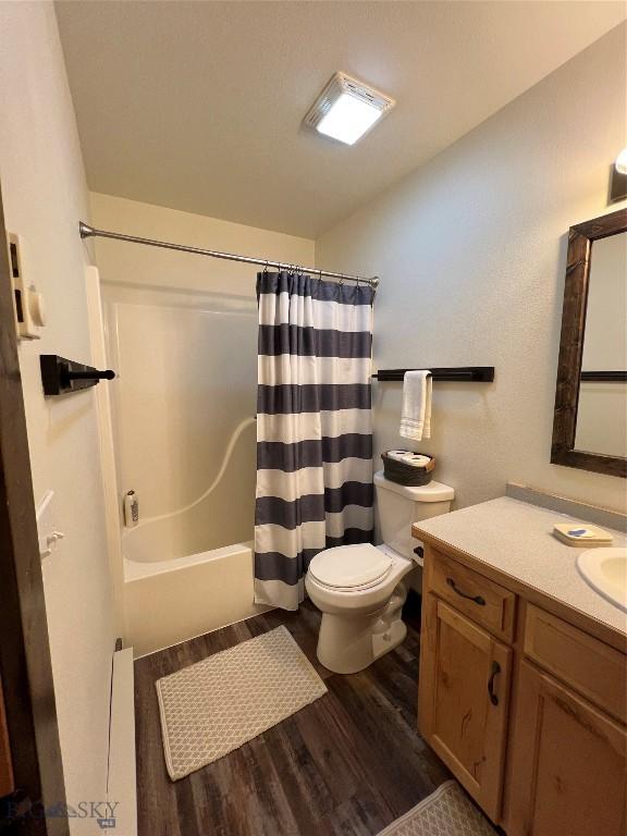 full bathroom featuring hardwood / wood-style flooring, toilet, vanity, and shower / bath combination with curtain