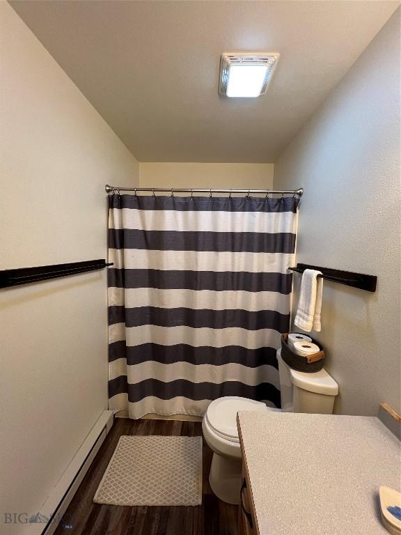 bathroom featuring toilet, hardwood / wood-style flooring, a baseboard heating unit, vanity, and curtained shower