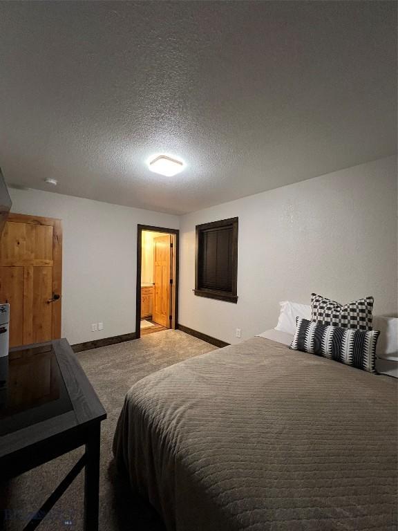 bedroom featuring a textured ceiling, carpet floors, and ensuite bath