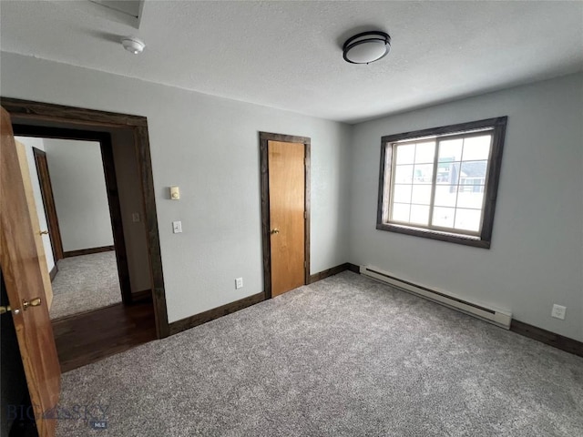 unfurnished bedroom featuring dark carpet and a baseboard heating unit