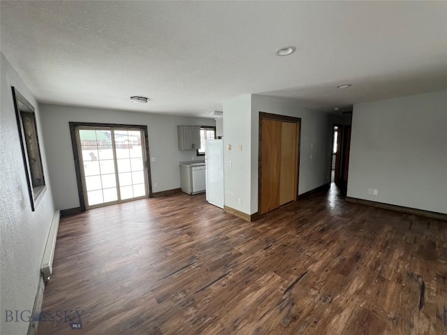 unfurnished living room featuring dark wood-type flooring and a baseboard heating unit