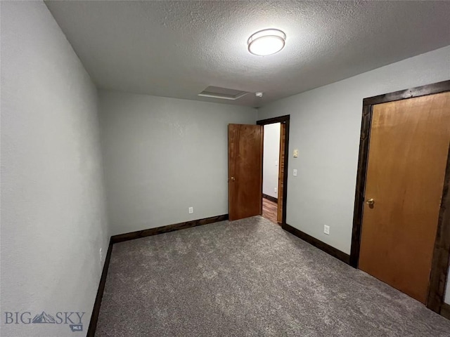 spare room with dark carpet and a textured ceiling