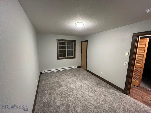 carpeted spare room featuring a textured ceiling and a baseboard radiator