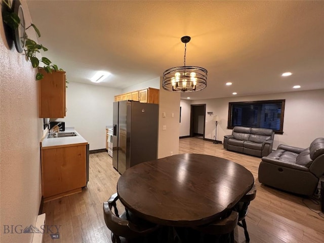 dining room with sink, an inviting chandelier, and light hardwood / wood-style flooring