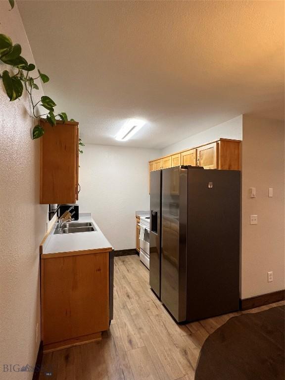 kitchen with stainless steel fridge with ice dispenser, white range with electric stovetop, light wood-type flooring, and sink