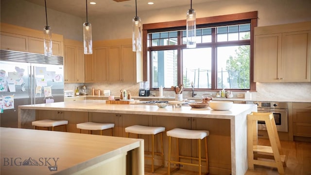 kitchen with appliances with stainless steel finishes, a breakfast bar area, light brown cabinetry, and decorative backsplash