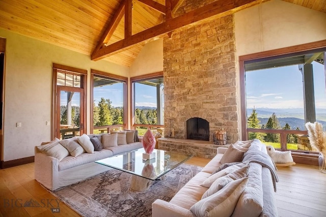 interior space with a stone fireplace, high vaulted ceiling, beamed ceiling, a mountain view, and light wood-type flooring