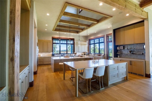 kitchen featuring a breakfast bar, tasteful backsplash, hanging light fixtures, a large island, and light hardwood / wood-style floors