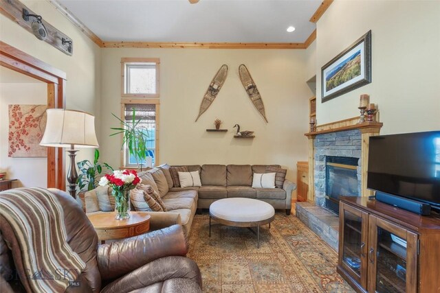 living room with ornamental molding and a stone fireplace