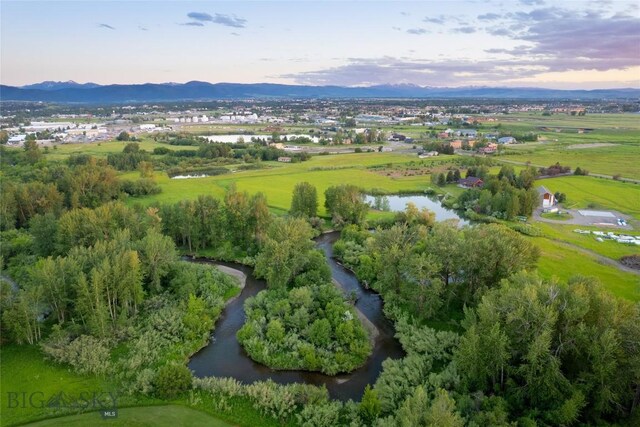 aerial view at dusk featuring a water and mountain view