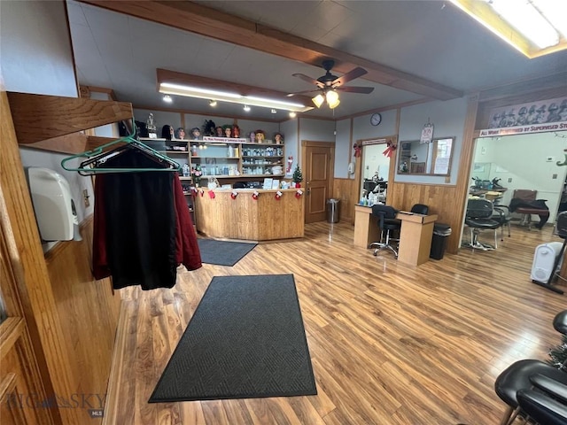 interior space featuring ceiling fan, wood-type flooring, wooden walls, and bar