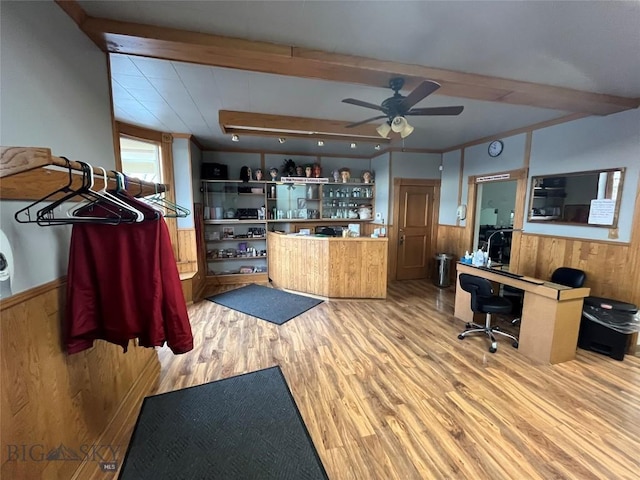 kitchen featuring ceiling fan, beam ceiling, hardwood / wood-style floors, and wooden walls