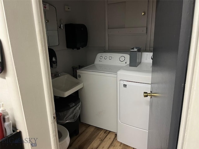 laundry area featuring light hardwood / wood-style flooring, washing machine and clothes dryer, and sink