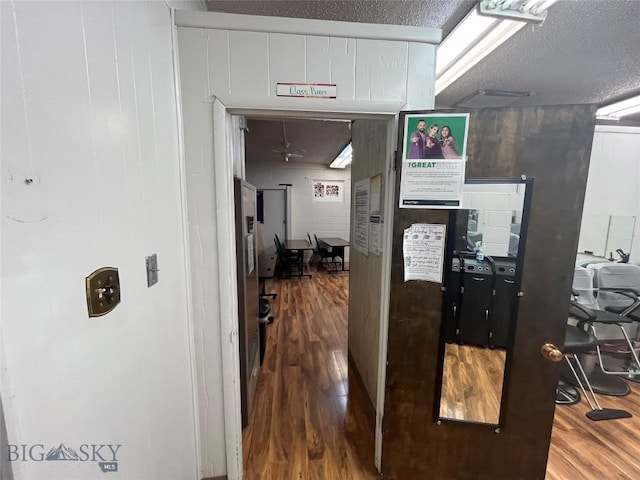 corridor with a textured ceiling and hardwood / wood-style flooring