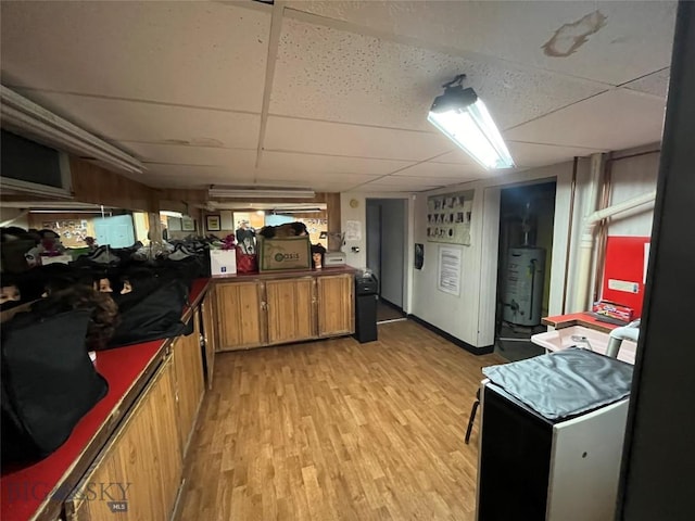 kitchen with water heater, light hardwood / wood-style floors, and a drop ceiling