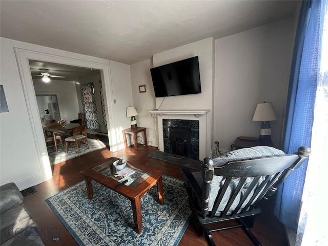 living room featuring ceiling fan, a high end fireplace, and wood-type flooring