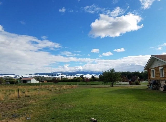 view of yard with a rural view, fence, and a mountain view