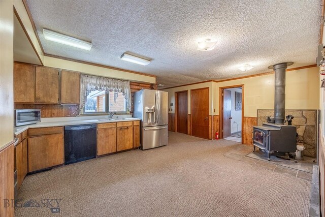 kitchen featuring a wainscoted wall, light countertops, brown cabinets, appliances with stainless steel finishes, and a sink