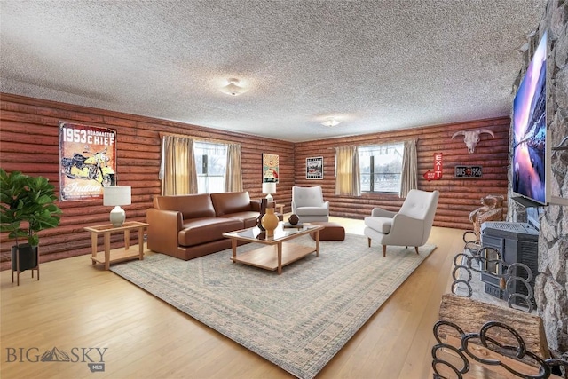 living area featuring plenty of natural light, a textured ceiling, a wood stove, and wood-type flooring