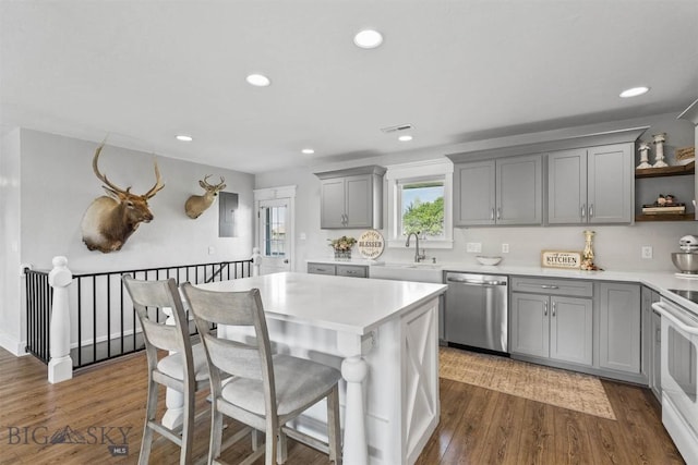 kitchen featuring a center island, sink, dark hardwood / wood-style floors, electric range, and stainless steel dishwasher