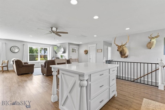 kitchen featuring light hardwood / wood-style flooring, a breakfast bar, white cabinets, and a kitchen island